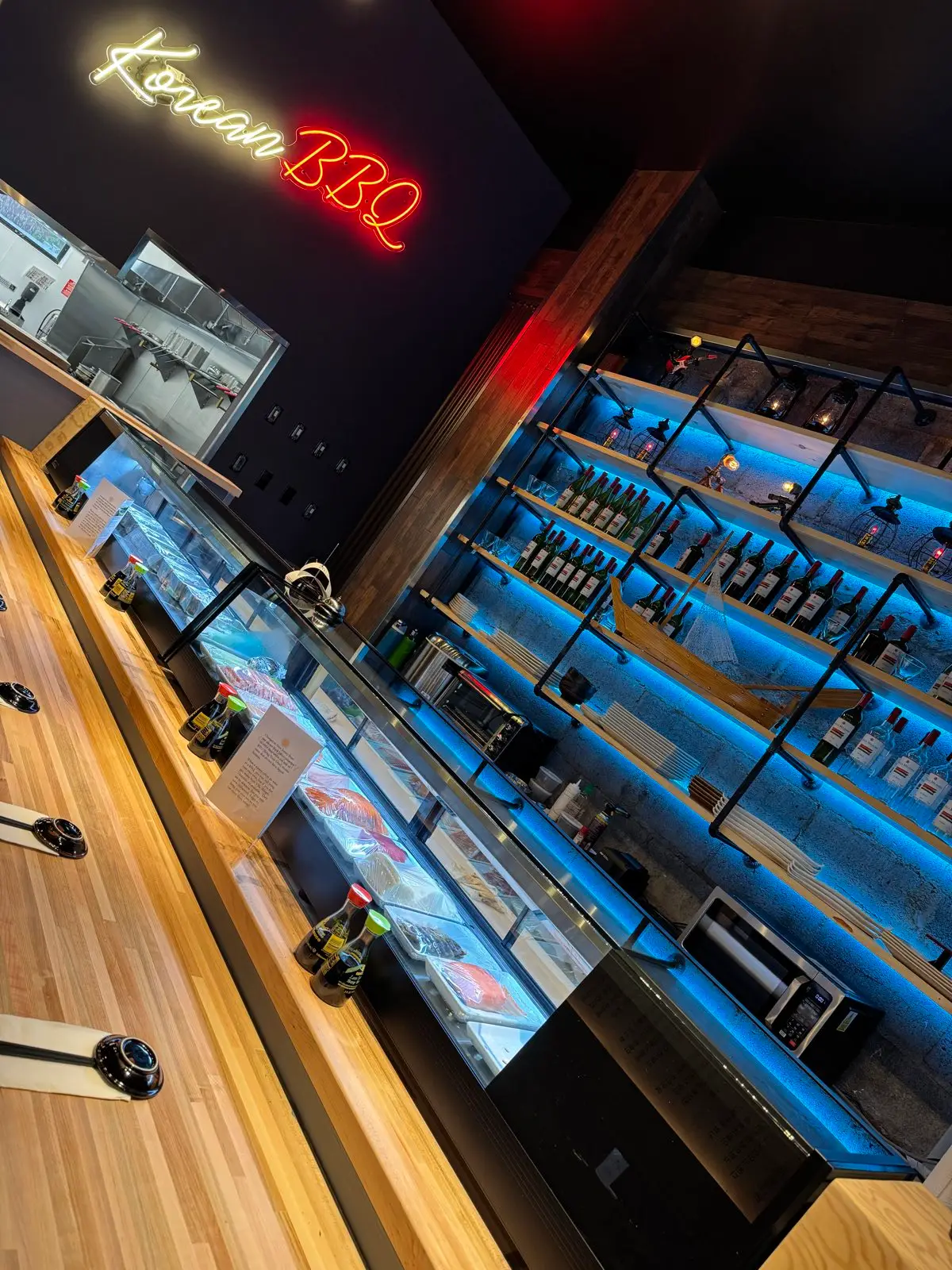 The sushi counter at Sendai, fish case lit beneath a red Korean BBQ neon
