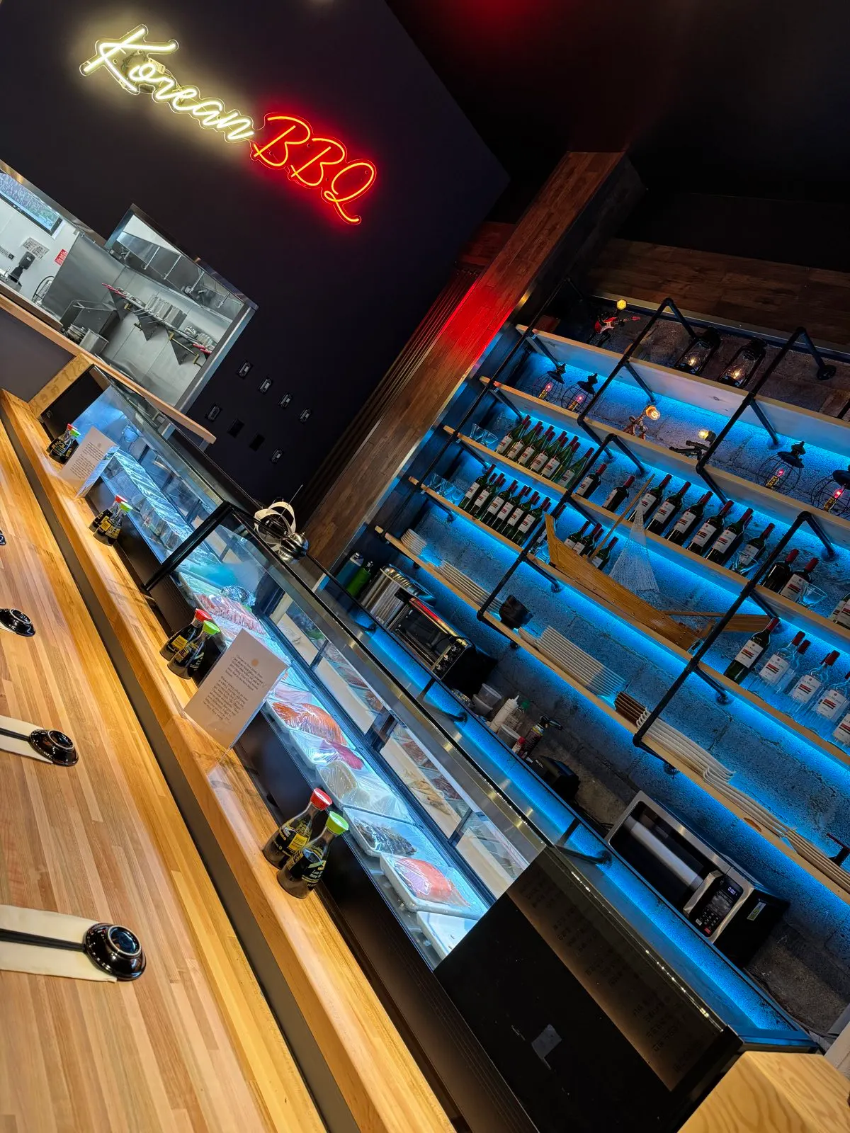 The sushi counter at Sendai, fish case lit beneath a red Korean BBQ neon