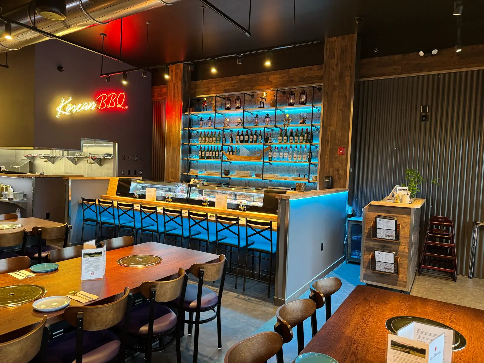 Grill tables and the sushi bar under a red Korean BBQ neon