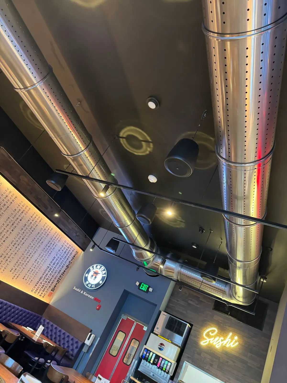 Polished steel extraction ducts running the length of the ceiling above the dining room